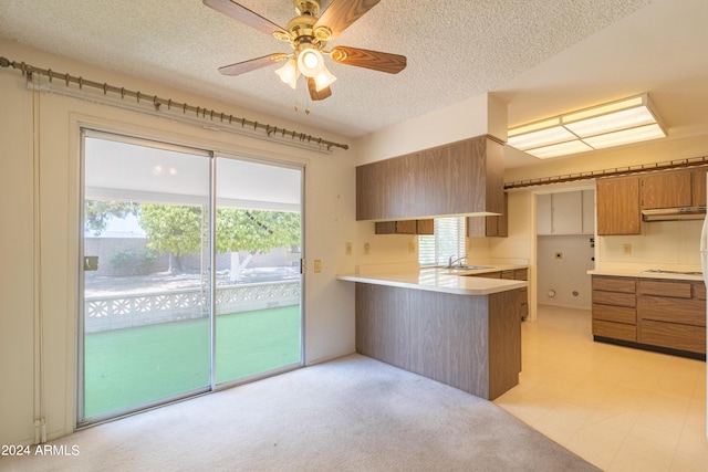 kitchen with ceiling fan, kitchen peninsula, a textured ceiling, and a wealth of natural light