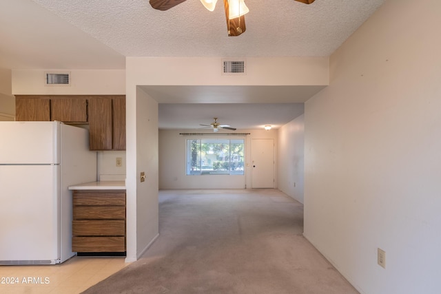 kitchen with ceiling fan, light colored carpet, white fridge, and a textured ceiling