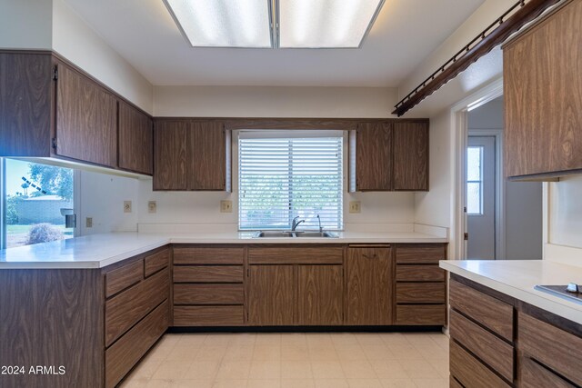 kitchen with plenty of natural light, kitchen peninsula, sink, and dark brown cabinets