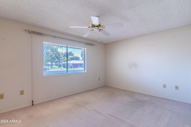 unfurnished room featuring ceiling fan, light carpet, and a textured ceiling