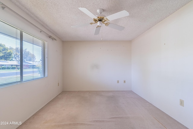 spare room with ceiling fan, light carpet, and a textured ceiling