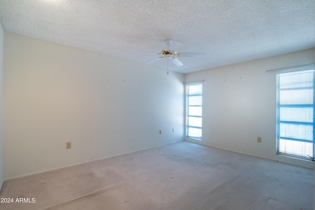 carpeted empty room with ceiling fan and a textured ceiling