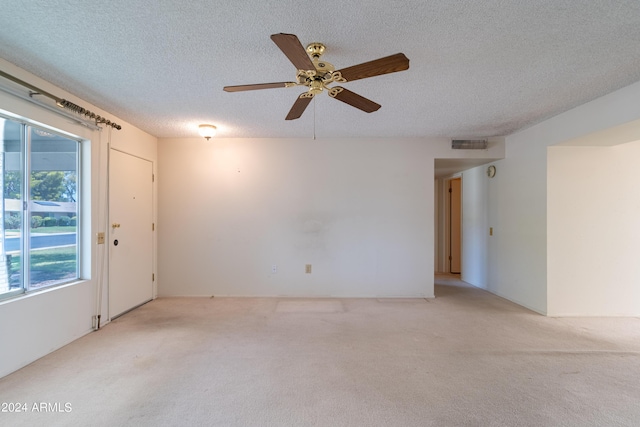 unfurnished room featuring ceiling fan, light carpet, and a textured ceiling