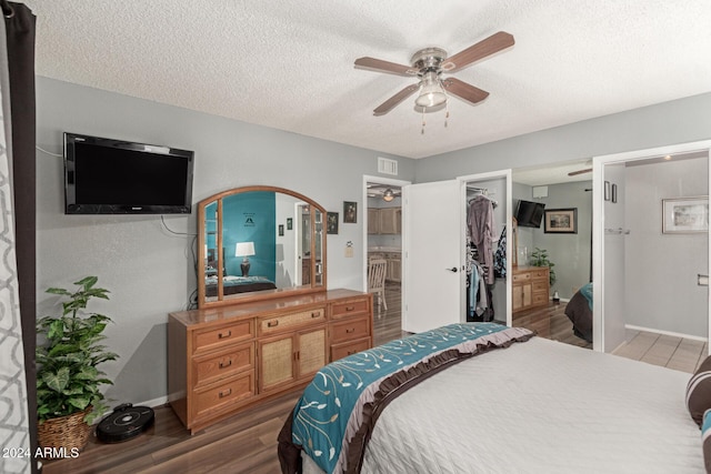 bedroom with dark wood-type flooring, connected bathroom, a spacious closet, a textured ceiling, and a closet