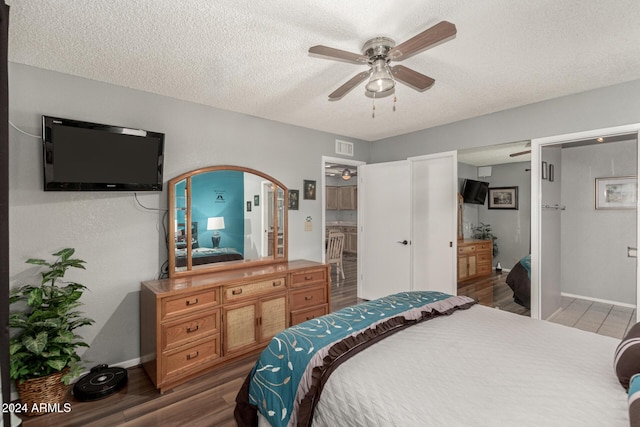 bedroom with ceiling fan, dark hardwood / wood-style floors, a textured ceiling, and ensuite bath