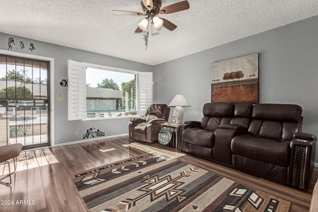 living room with ceiling fan, dark wood-type flooring, and a textured ceiling