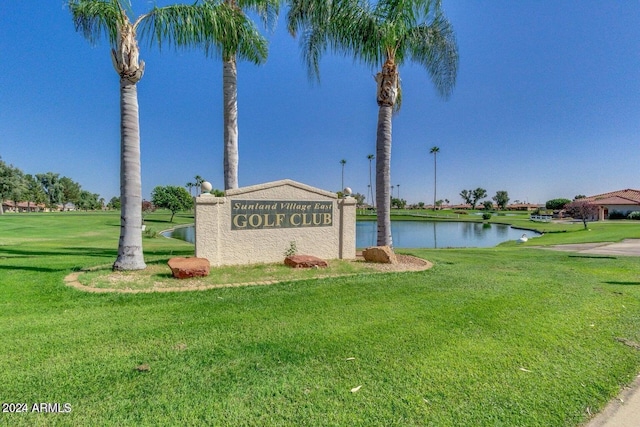 community sign featuring a yard and a water view