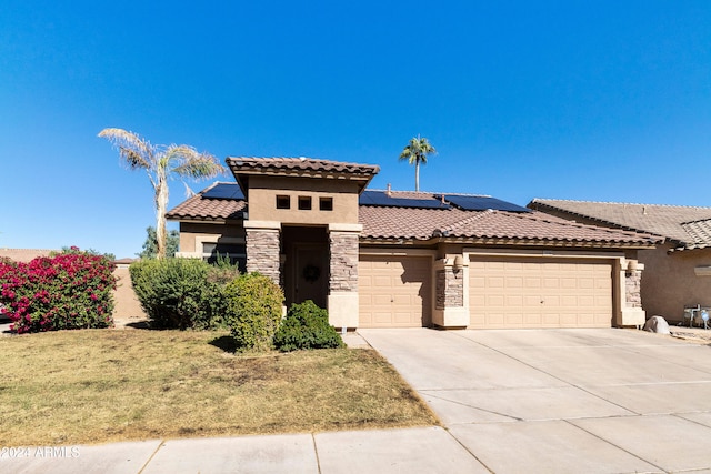 mediterranean / spanish house with a front yard, a garage, and solar panels