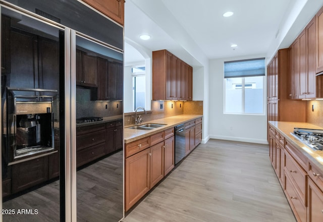 kitchen with sink, tasteful backsplash, black dishwasher, stainless steel gas stovetop, and light hardwood / wood-style floors