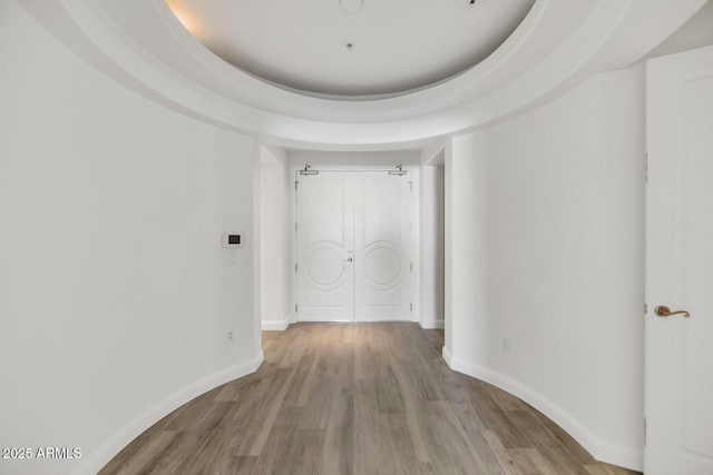 hallway featuring a tray ceiling and light wood-type flooring