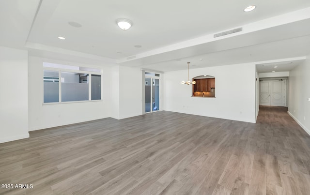 unfurnished living room with wood-type flooring and a chandelier