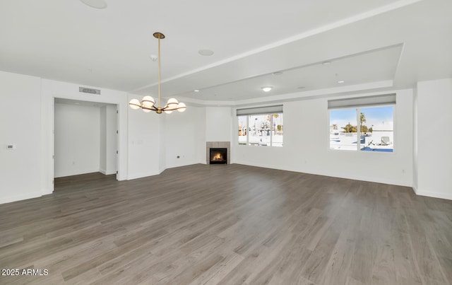 unfurnished living room featuring wood-type flooring and a notable chandelier