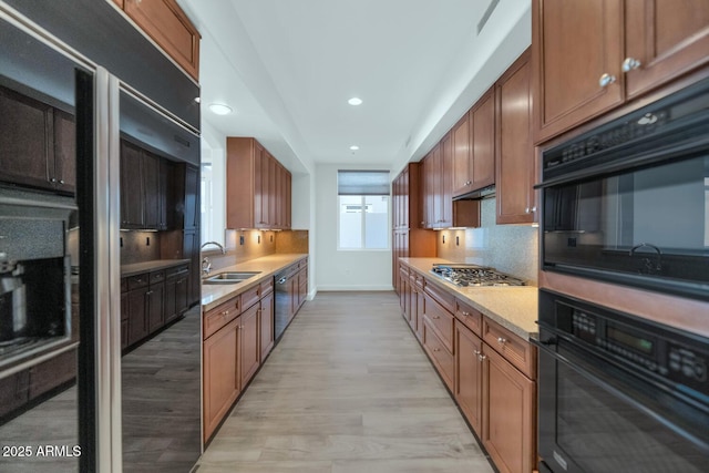 kitchen with tasteful backsplash, sink, black appliances, and light wood-type flooring