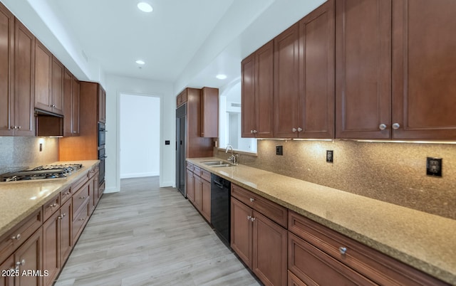 kitchen with tasteful backsplash, black appliances, sink, light hardwood / wood-style floors, and light stone counters