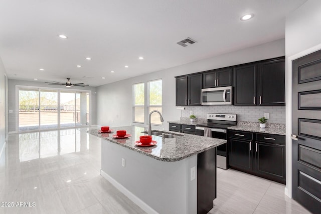 kitchen with light stone countertops, visible vents, a sink, appliances with stainless steel finishes, and backsplash