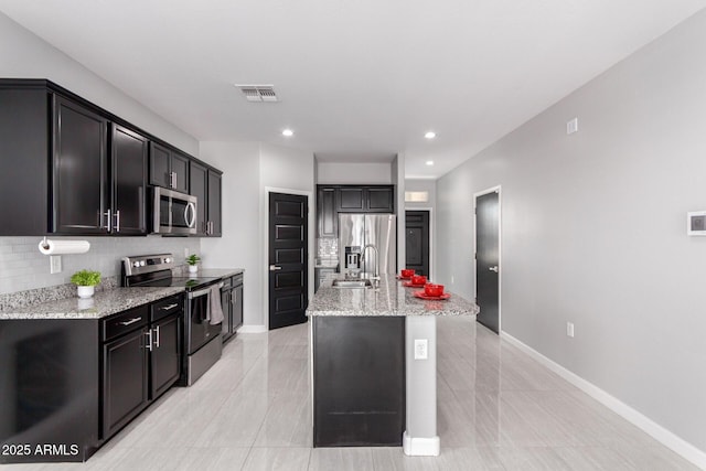 kitchen featuring visible vents, a sink, backsplash, appliances with stainless steel finishes, and light stone countertops