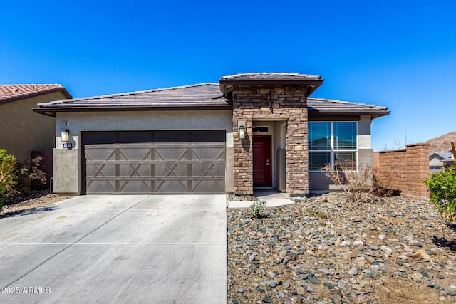 prairie-style house featuring stucco siding, driveway, stone siding, a garage, and a tiled roof