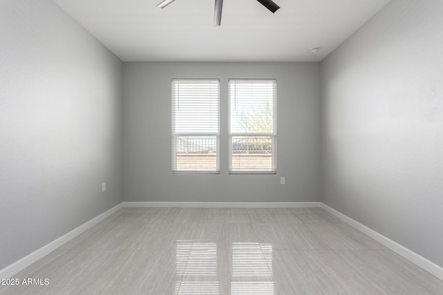 empty room with a ceiling fan and baseboards