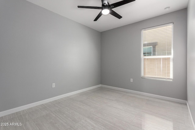 unfurnished room with a ceiling fan and baseboards