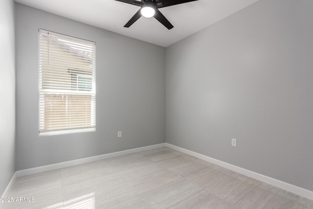 spare room featuring a ceiling fan, a healthy amount of sunlight, and baseboards