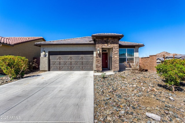 prairie-style house with a tiled roof, concrete driveway, stucco siding, a garage, and stone siding