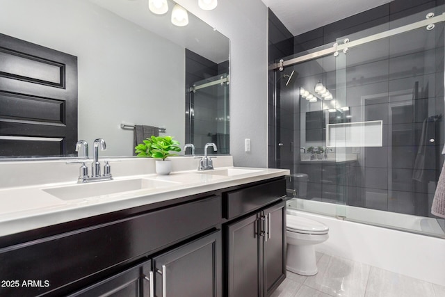 full bath featuring double vanity, shower / bath combination with glass door, toilet, and a sink