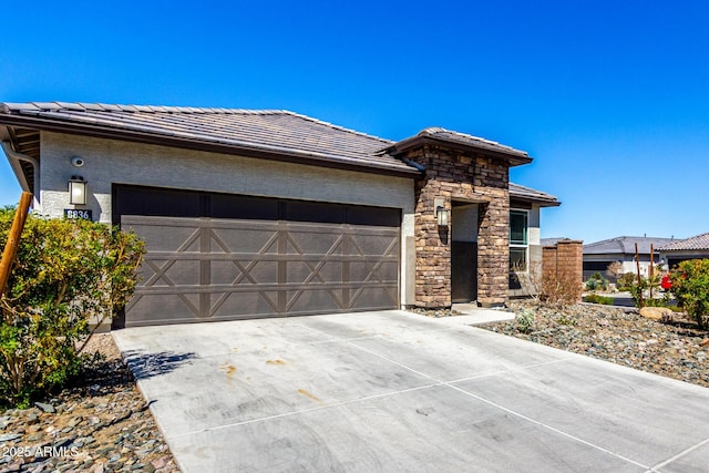 view of front of property with concrete driveway, a garage, stone siding, and stucco siding