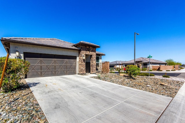 prairie-style home featuring an attached garage, stucco siding, concrete driveway, stone siding, and a tile roof