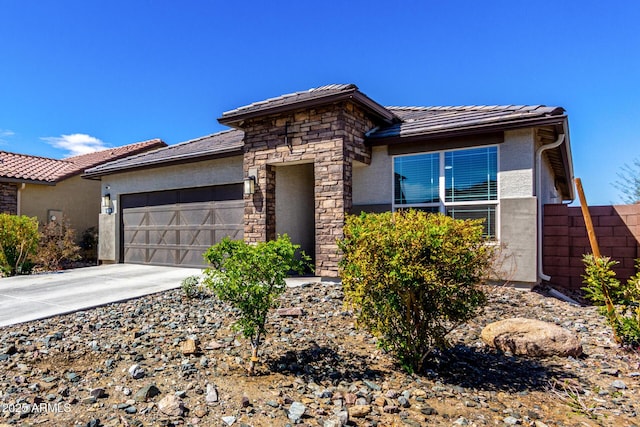 prairie-style home featuring a garage, stone siding, concrete driveway, and stucco siding