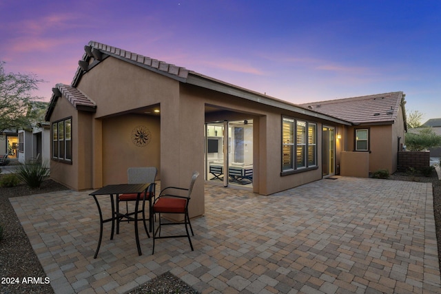 back house at dusk with a patio area