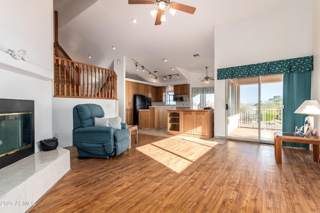 living room featuring a fireplace, high vaulted ceiling, and light wood-type flooring