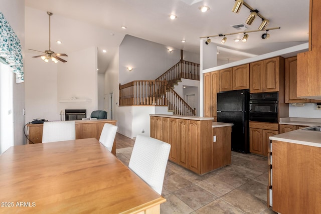 kitchen with ceiling fan, a large fireplace, high vaulted ceiling, and black appliances