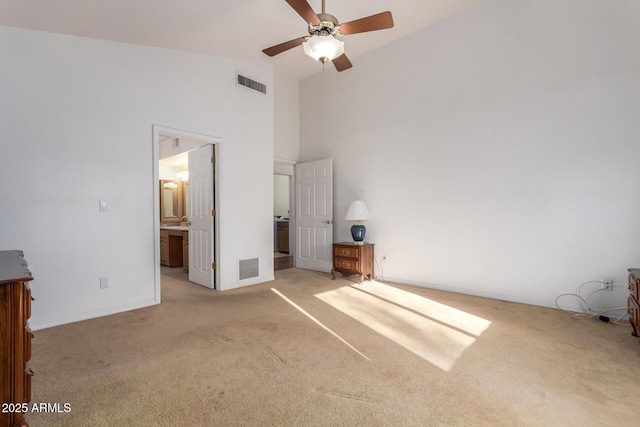 unfurnished bedroom with light carpet, ensuite bath, and high vaulted ceiling