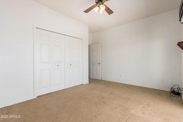 unfurnished bedroom featuring ceiling fan, light colored carpet, and a closet