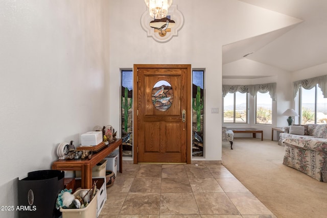 entrance foyer featuring high vaulted ceiling, a chandelier, and carpet flooring