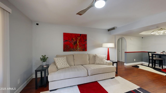 living area featuring arched walkways, wood finished floors, a ceiling fan, and baseboards