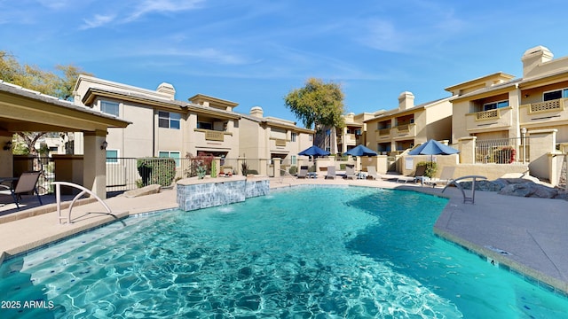 community pool with a patio area, a residential view, and fence