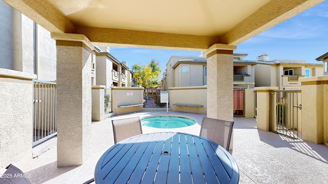 view of patio with a hot tub, a residential view, and fence