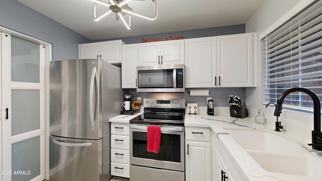 kitchen with appliances with stainless steel finishes, a sink, and white cabinets