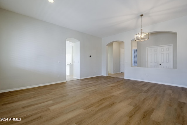 unfurnished room featuring a notable chandelier and light hardwood / wood-style flooring