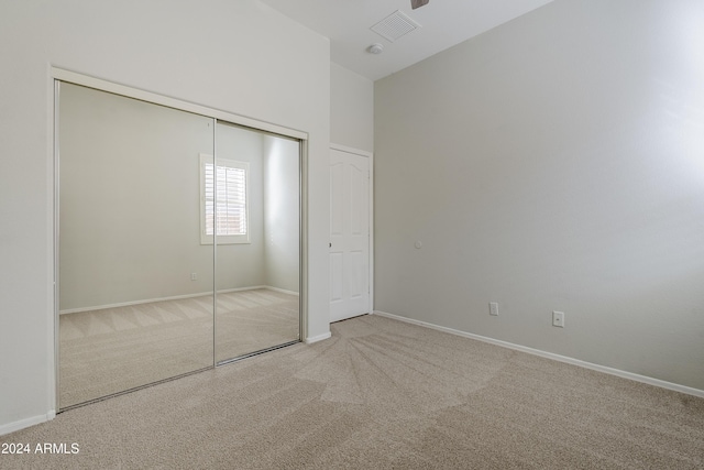 unfurnished bedroom with light colored carpet and a closet