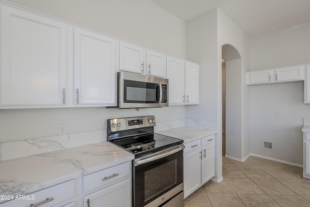 kitchen featuring light stone countertops, light tile patterned floors, stainless steel appliances, and white cabinetry