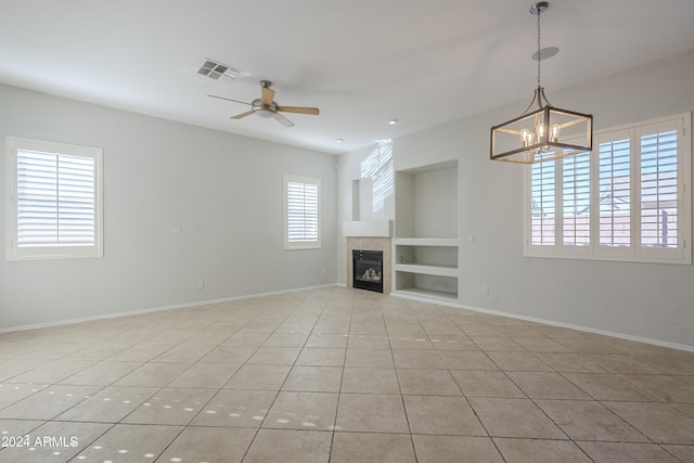 unfurnished living room featuring built in features, a healthy amount of sunlight, and light tile patterned flooring