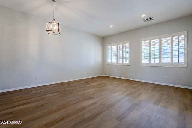 unfurnished room featuring hardwood / wood-style flooring and an inviting chandelier