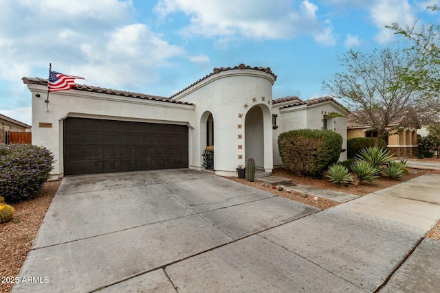 mediterranean / spanish house featuring stucco siding, an attached garage, driveway, and a tiled roof