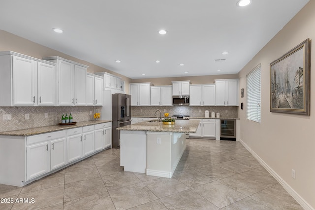 kitchen featuring white cabinetry, appliances with stainless steel finishes, beverage cooler, and light stone countertops