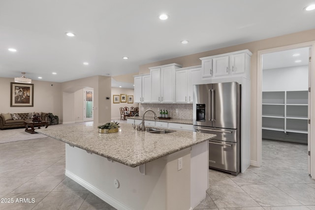 kitchen with white cabinetry, sink, high quality fridge, and a center island with sink