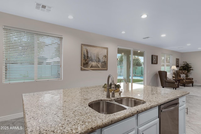 kitchen with sink, dishwasher, white cabinetry, light stone countertops, and light tile patterned flooring