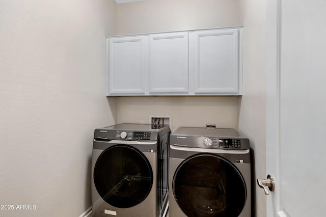 clothes washing area featuring cabinets and washer and dryer