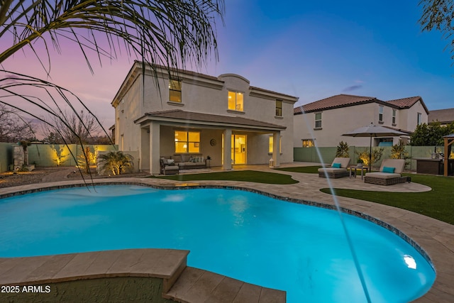 pool at dusk with pool water feature, an outdoor hangout area, and a patio